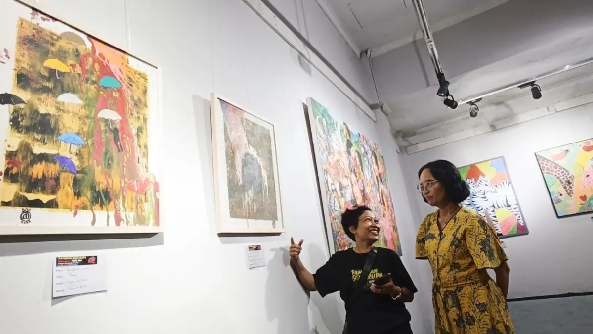 Pengunjung mengamati lukisan yang dipamerkan di Galeri Prabangkara, Surabaya, Selasa (5/5). ANDY SATRIA/RADAR SURABAYA