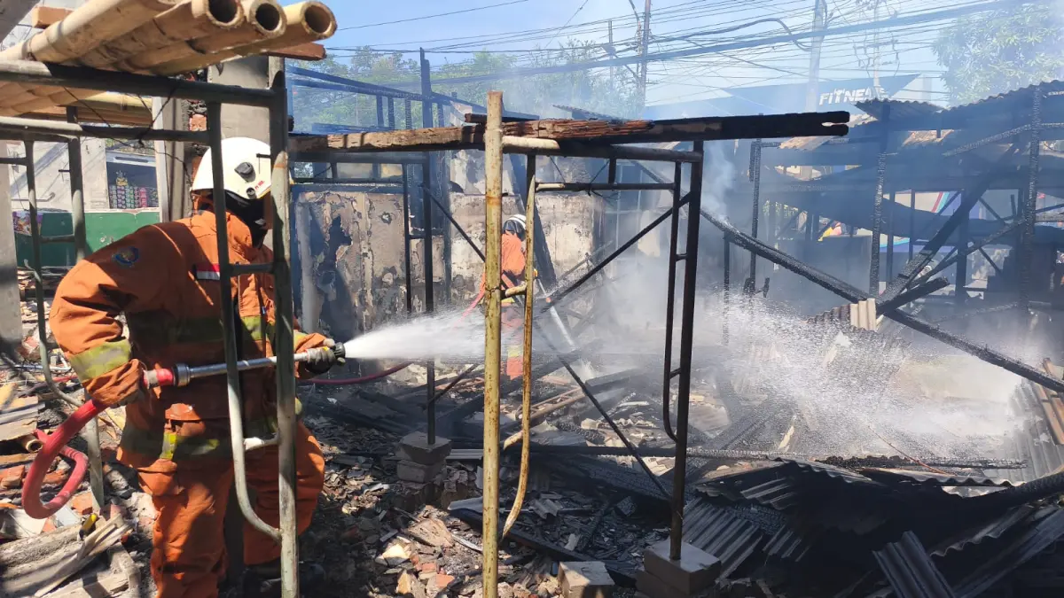 SEMPROT: Petugas DPKP Surabaya saat berupaya melakukan pembasahan gudang proyek yang terbakar di Jalan Menganti, Surabaya.(IST/RADAR SURABAYA)