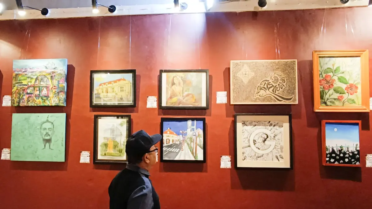 Pengunjung menyaksikan pameran lukisan di Galeri Merah Putih, Balai Pemuda Surabaya. (ANDY SATRIA/RADAR SURABAYA) 