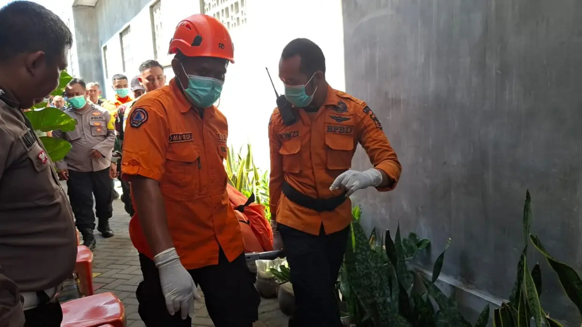 PENYELIDIKAN: Petugas mengevakuasi jenazah korban pemuda yang ditemukan tewas di rumah kontrakan Gayungan, Surabaya. (MAHRUS/RADAR SURABAYA)