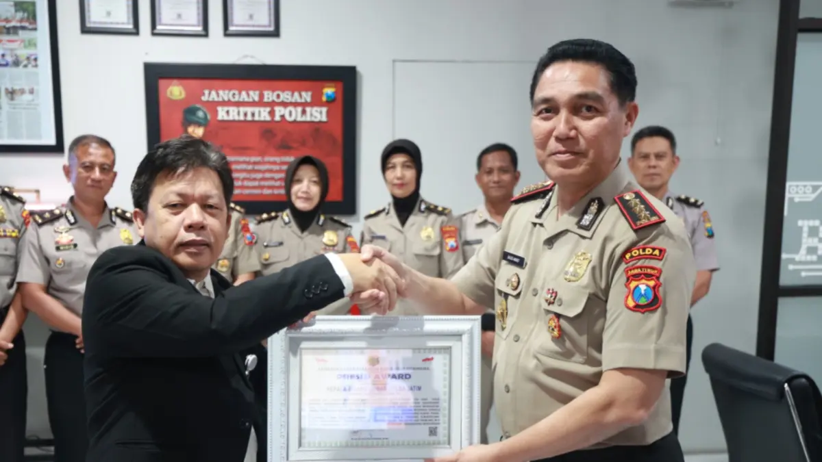 INFORMATIF: Direktur Eksekutif Lemkapi, Edi Hasibuan (kiri), menyerahkan piagam apresiasi pada Kepala Bidhumas Polda Jatim.(IST/RADAR SURABAYA)