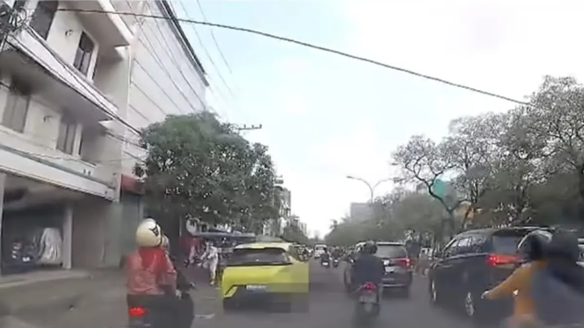TEREKAM: Mobil listrik (kuning) saat melindas pengendara motor yang terjatuh dari motornya di Jalan Kedungdoro, Surabaya. (IST/RADAR SURABAYA)