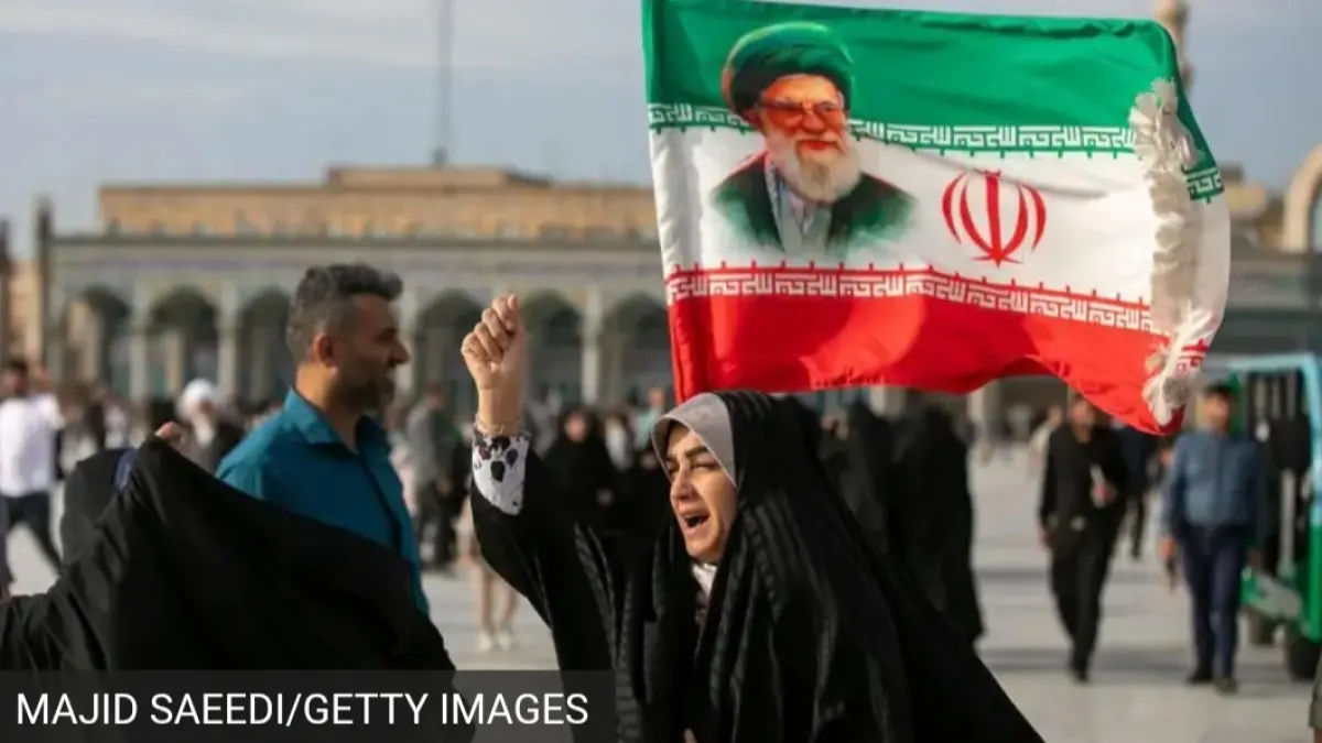 Seorang perempuan terlihat membawa bendera dengan gambar mantan Pemimpin Tertinggi Iran, Ayatollah Ali Khamenei selama Idul Adha pada 26 Mei 2026 di Qom, Iran. (BBC) 