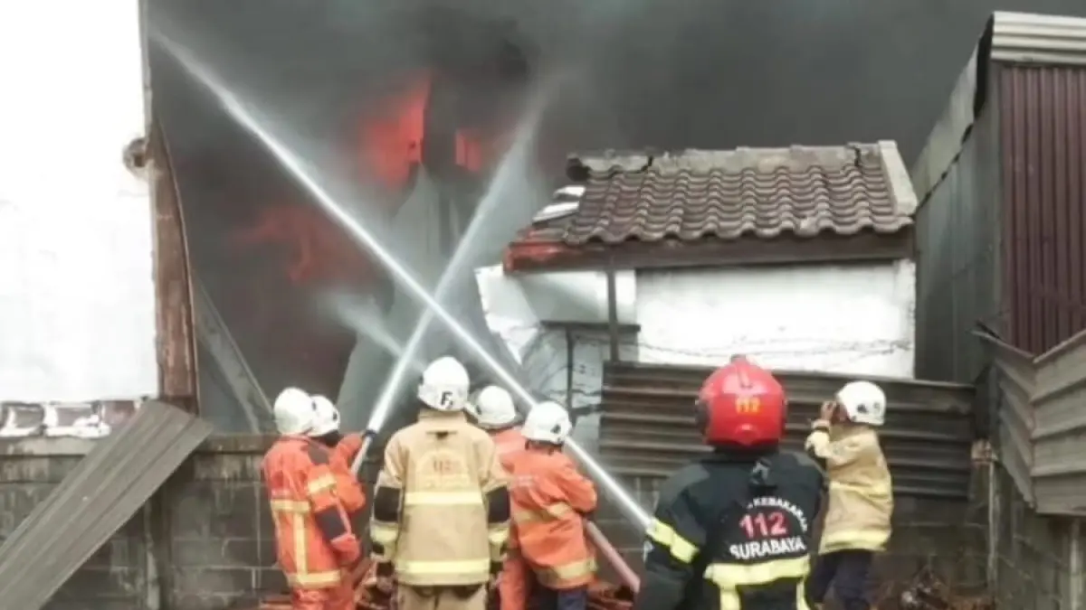 Petugas melakukan pembasahan bangunan yang terbakar di Surabaya. (IST)