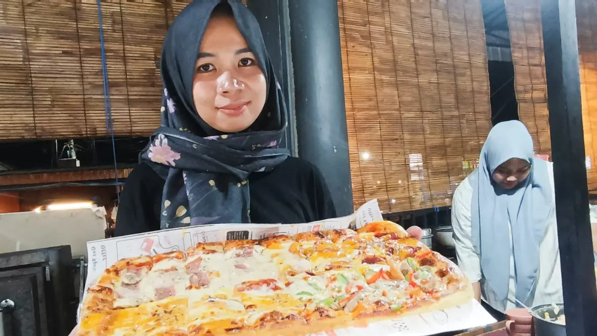 Iin Indriyana menunjukkan cara membuat pizza long di Jalan Tidar Surabaya. (Andy Satria/Radar Surabaya)