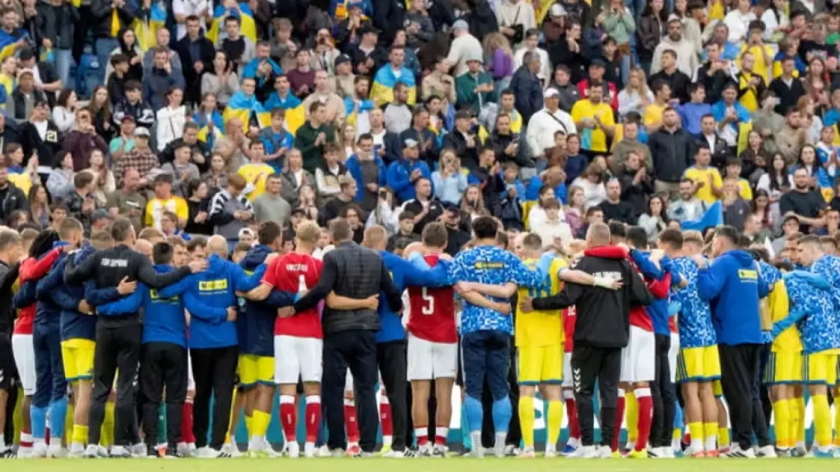 Pemain Denmark dan Ukraina berkumpul dalam sebuah lingkaran setelah Christian Eriksen dibawa pergi menggunakan ambulans dari Stadion Odense pada Minggu.
(Foto: Bo Amstrup/EPA) 
