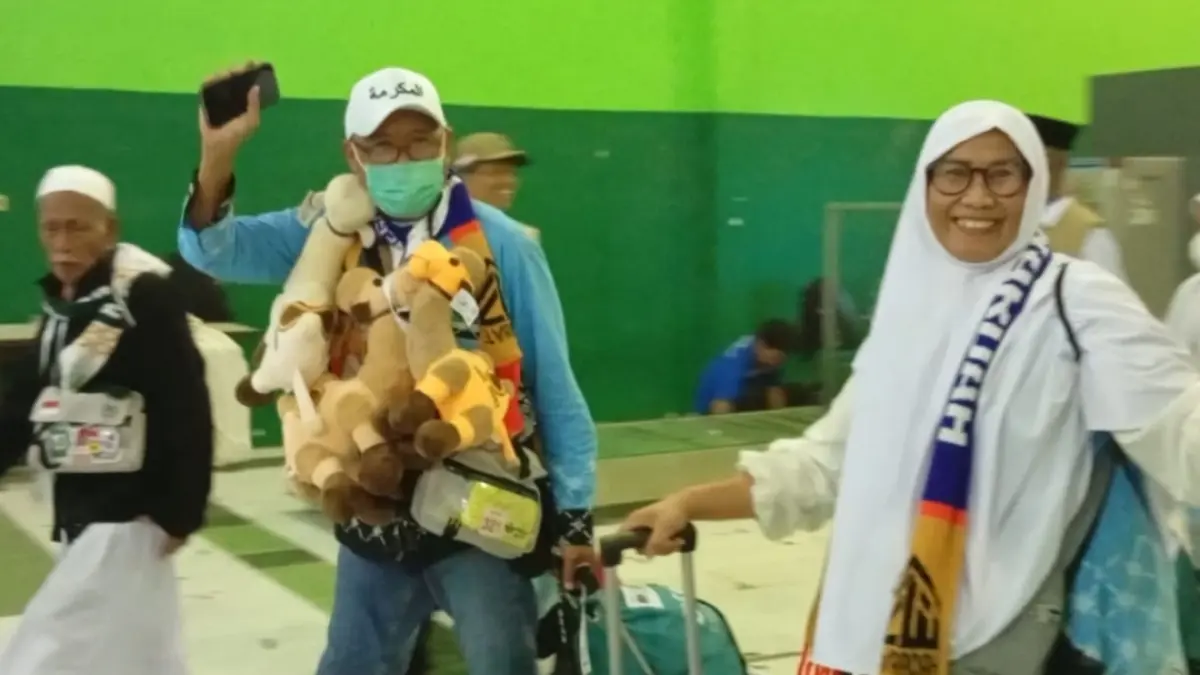 Jemaah haji setibanya di Tanah Air terlihat mengalungkan boneka unta sebagai oleh-oleh. (Rahmat Sudrajat) 