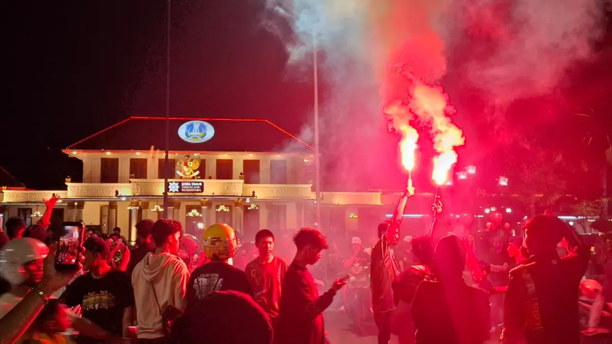 MENYALA: Beberapa suporter menyalakan flare di depan Gedung Negara Grahadi, Surabaya. (GUNTUR IRIANTO/RADAR SURABAYA)