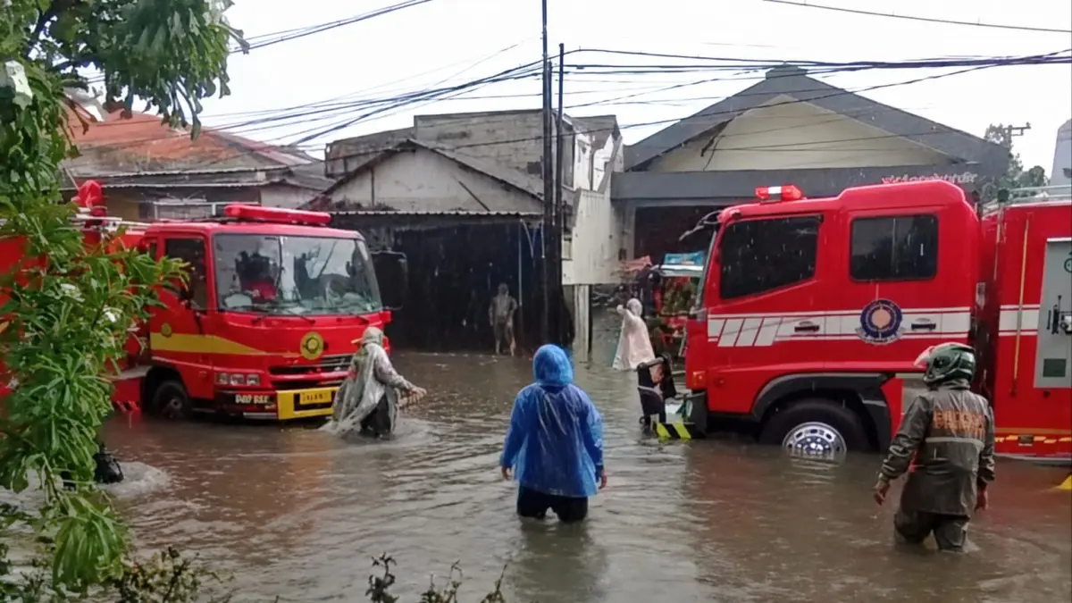 SIAGA: Petugas DPKP Surabaya membantu mengatasi genangan yang terjadi di beberapa titik wilayah Surabaya akibat hujan deras dan pasang air laut.(IST/RADAR SURABAYA)