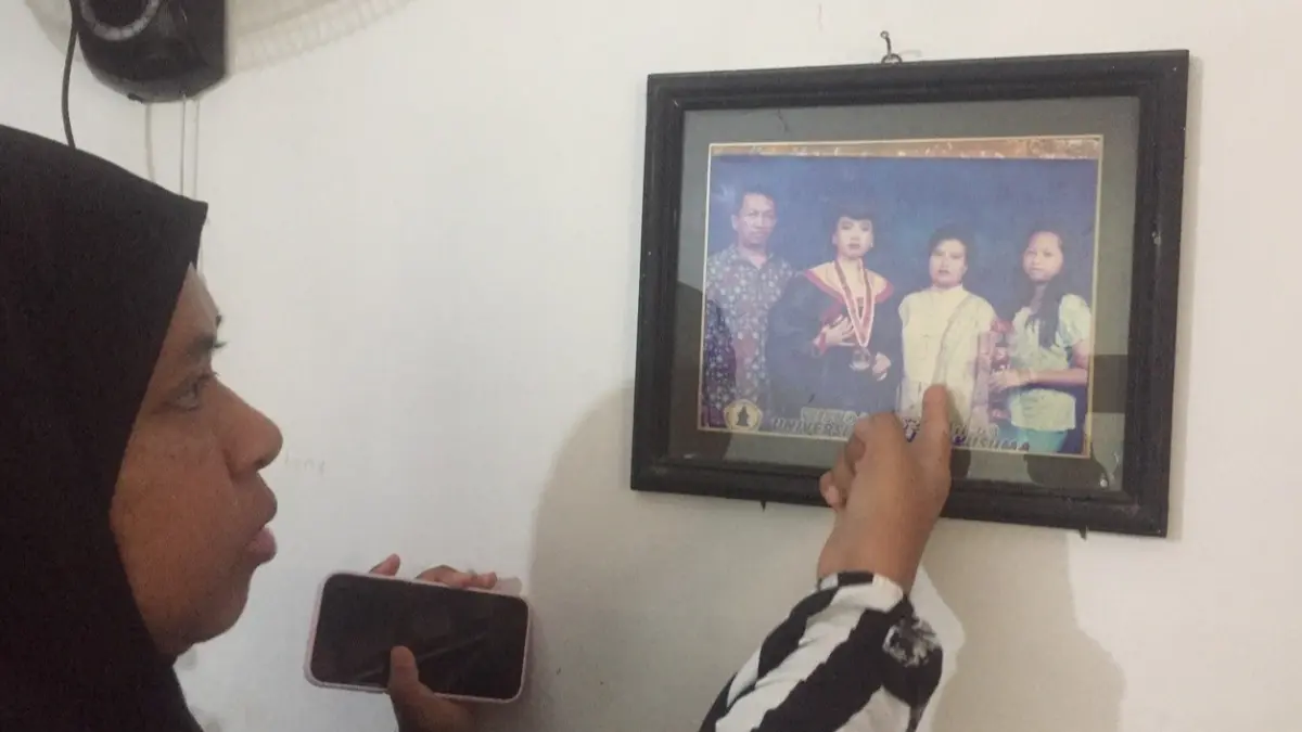 BERDUKA: Ponakan korban menunjukkan foto korban semasa hidup. W ditemukan meninggal tak wajar di rumahnya Jalan Candi Lontar, Surabaya. (IST/RADAR SURABAYA)