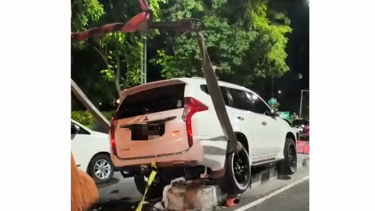 BUKAN ATRAKSI: Petugas mengevakuasi mobil yang naik pembatas jalan di Jalan Mayjen Sungkono, Surabaya. (IST/RADAR SURABAYA)