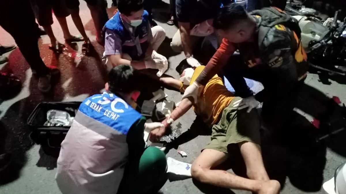 TAK SADAR : Petugas saat memberikan bantuan medis korban pengendara motor di Jalan Kenjeran, Surabaya, Sabtu (27/6). Ia menabrak mobil parkir. (IST/RADAR SURABAYA)