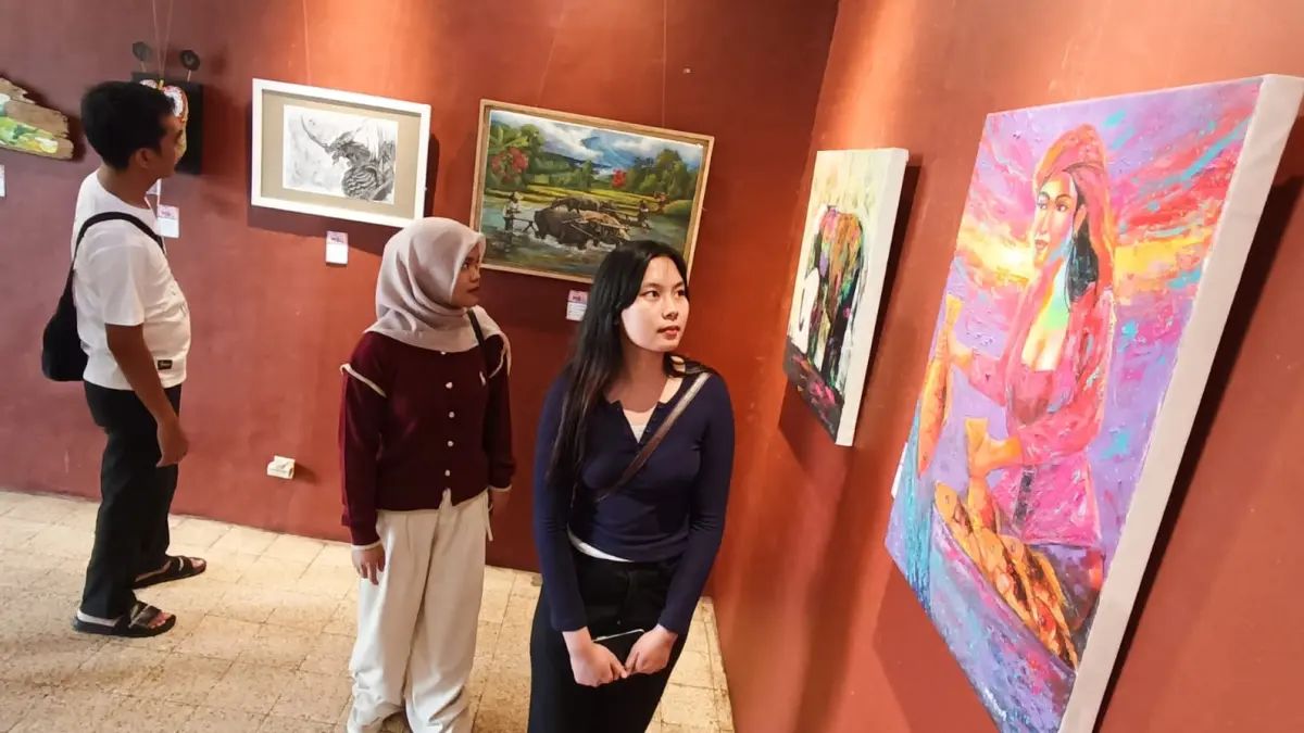 Pengunjung menikmati lukisan yang dipamerkan di Balai Pemuda Surabaya. (ANDY SATRIA/RADAR SURABAYA) 
