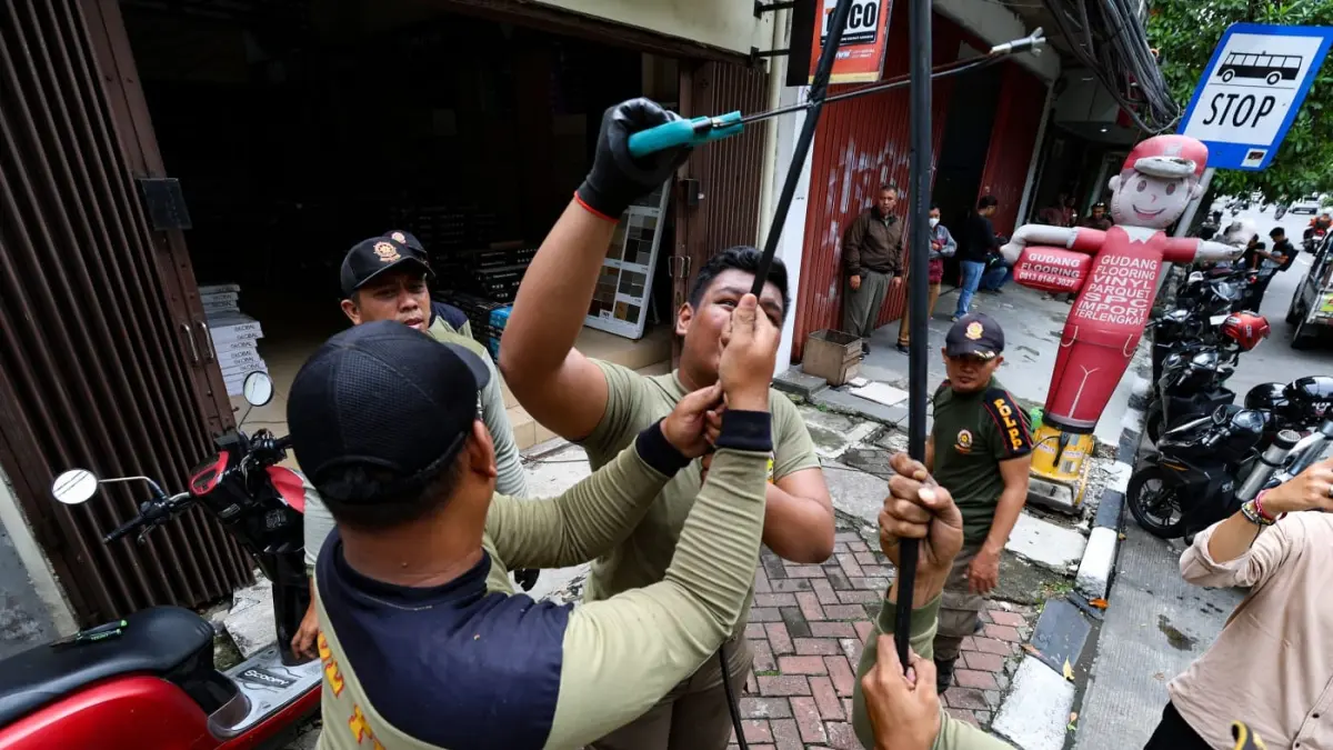 Petugas satpol PP memutus kabel optik yang tidak berizin di Surabaya. (HO)