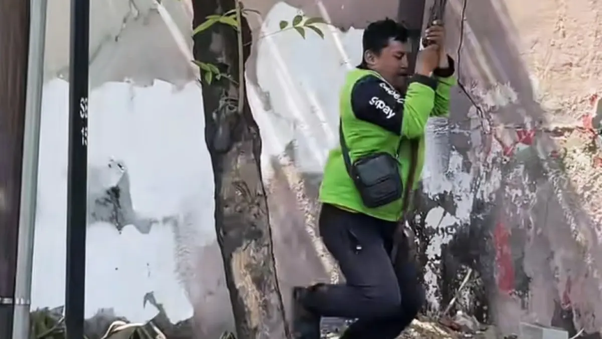VIRAL: Pengemudi ojol bermain ayunan menggunakan akar pohon di bawah viaduk sekitar Stasiun Gubeng, Surabaya.