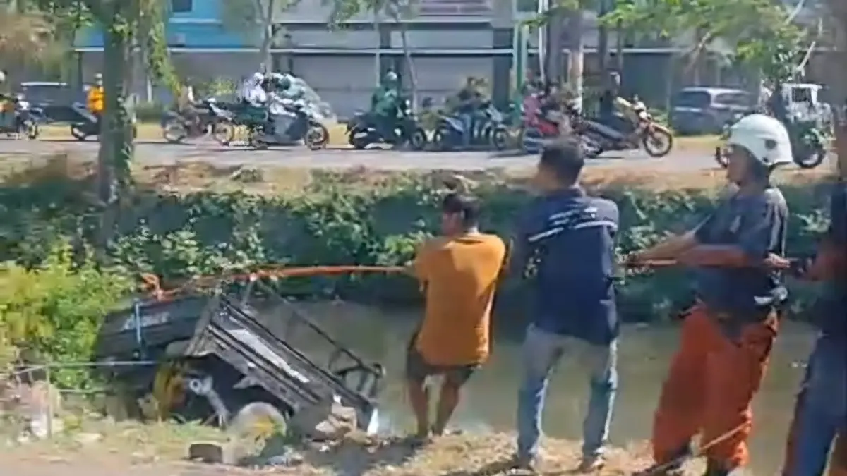 DITARIK : Petugas dibantu warga mengevakuasi kendaraan roda tiga yang tercebur di sungai Jalan Medayu Indah Regency Surabaya, Senin (27/7).(IST/RADAR SURABAYA)