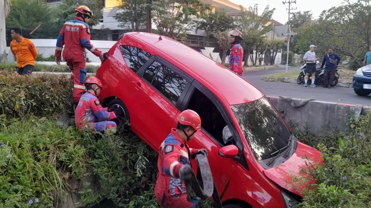 NYUNGSEP : Tim Rescue DPKP Surabaya mengevakuasi mobil milik A yang tercebur selokan di Jalan Dharmahusada Indah I, Surabaya, Selasa (28/7).(IST/RADAR SURABAYA)