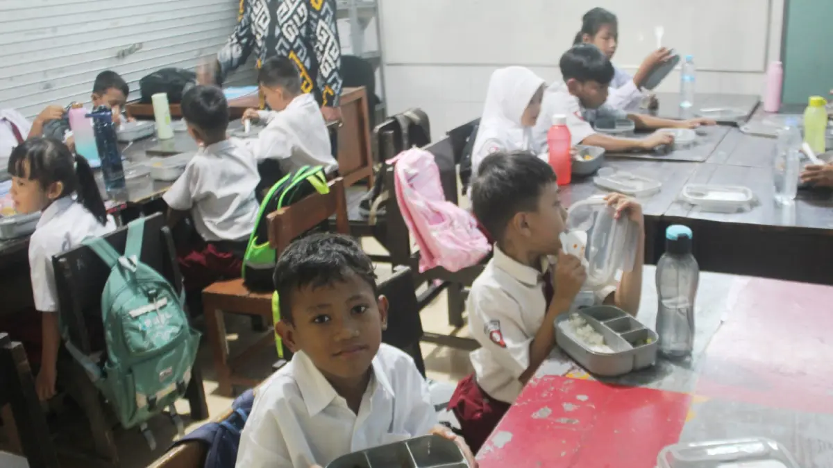Anak-anak sekolah menikmati menu MBG di Surabaya. (RAHMAT SUDRAJAT/RADAR SURABAYA)