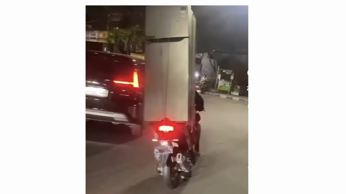 KOK BISA: Seorang pria mengendarai motor sambil membawa kulkas dua pintu di jalanan Kota Surabaya.