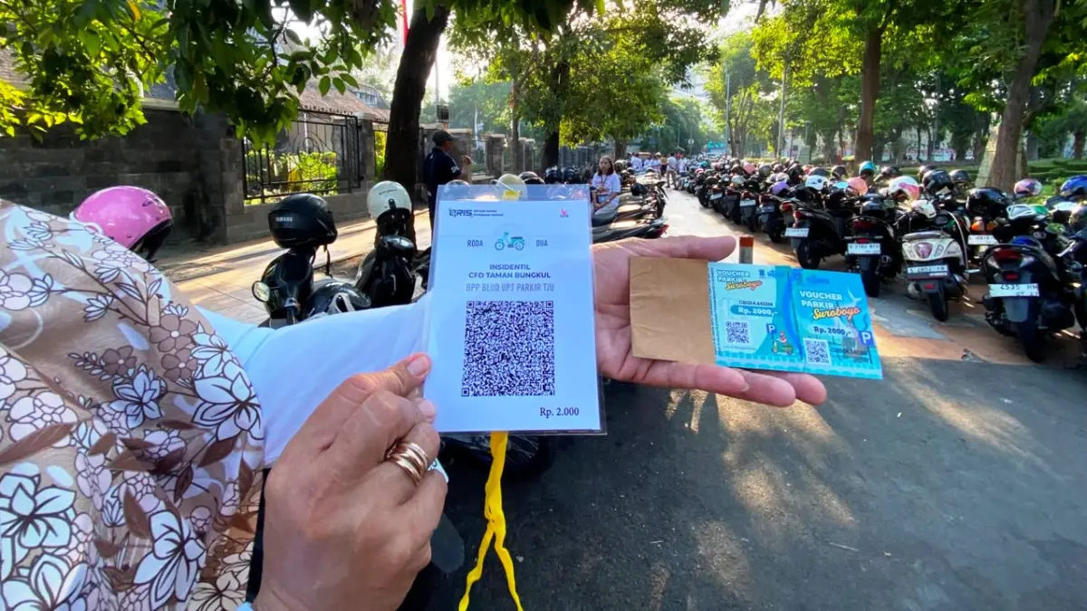 CEGAH KEBOCORAN: Petugas Dishub saat menjadi jukir dengan mengarahkan menggunakan QRIS atau kupon parkir.

