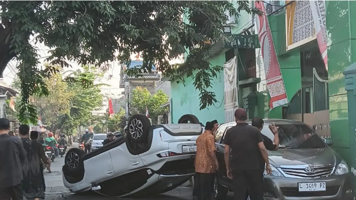MENUTUP JALAN : Kondisi mobil milik DS terbalik usai menabrak pohon di Jalan Jambangan Surabaya, Senin (17/8).(IST/RADAR SURABAYA)