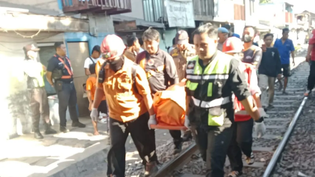 EVAKUASI: Petugas saat membawa jenazah korban terserempet KA di Jalan Krembangan, Surabaya. (IST/RADAR SURABAYA)