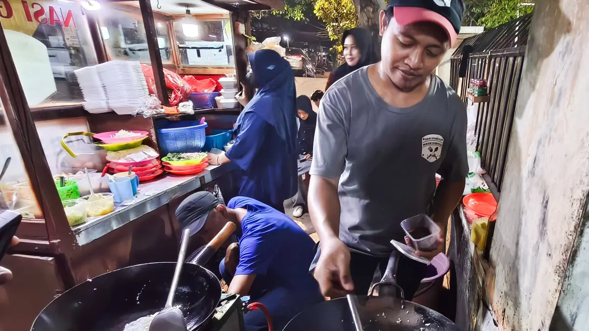 Ferdyan Ramadhani (kanan), menyiapkan menu nasi goreng kopi pesanan pelanggannya. (ANDY SATRIA/RADAR SURABAYA)&nbsp;