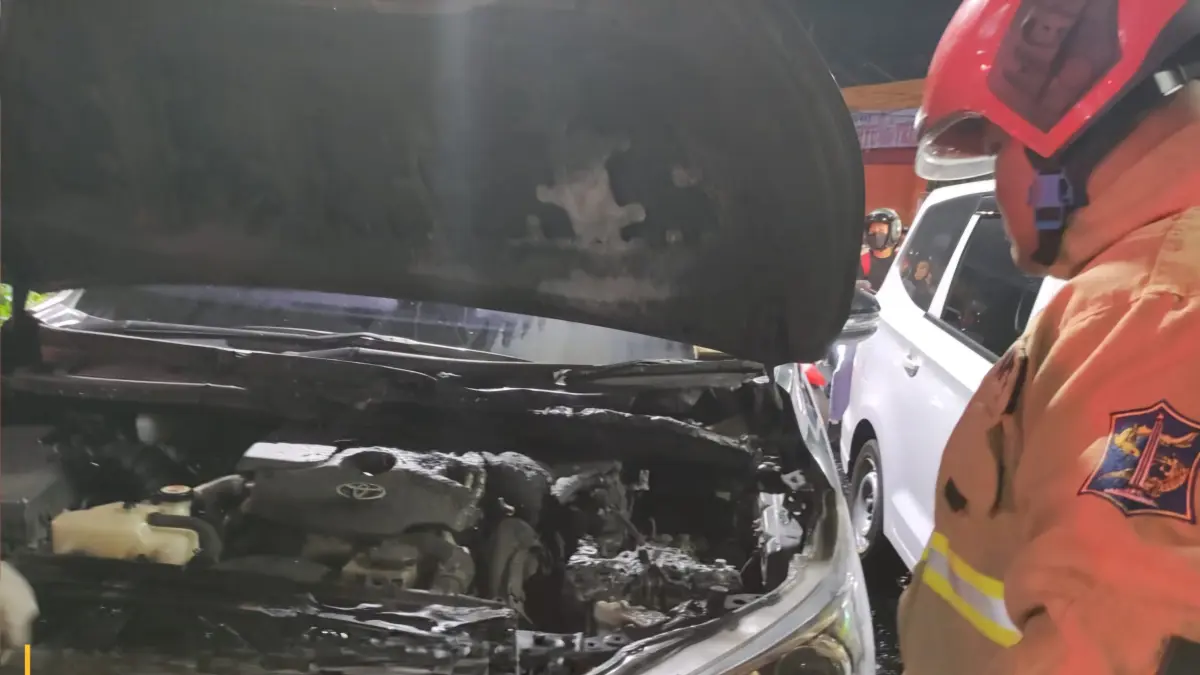NYARIS LUDES : Petugas mengecek kondisi kap mobil milik LJO yang terbakar di TL Jalan Banyu Urip arah Jalan Pasar Kembang, Senin (14/9) malam.(IST/RADAR SURABAYA)
