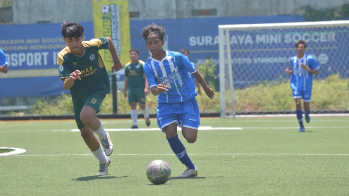 ADU LARI: Pemain SMAN 1 Manyar (biru) berupaya menggiring bola dalam turnamen Bahlil Mini Soccer. (ANDY SATRIA/RADAR SURABAYA)