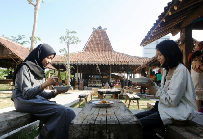 URI-URI BUDOYO: Pengunjung menikmati menu makanan yang disajikan dengan latar belakang bangunan Joglo khas Jawa, di resto kawasan Gunung Anyar, Sabtu (16/10). (ANDY SATRIA/RADAR SURABAYA)