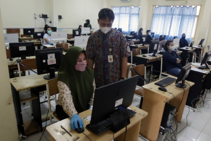 AWASI UJIAN: Penanggungjawab Bagian Registrasi dan Ujian UT Surabaya, Dwianto Asmara, S.Kom, mengecek kesiapan salah satu mahasiswa sebelum menjalankan Ujian Tugas Akhir Program (TAP) yang digelar secara online dan serentak, di SMKN 5 Surabaya, Sabtu (18/