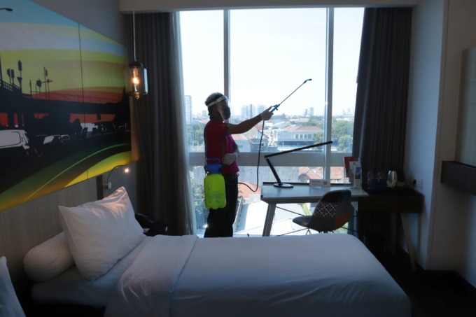 Karyawan hotel di Surabaya melakukan penyemprotan cairan disinfektan pada salah satu kamar. (ANDY SATRIA/RADAR SURABAYA)