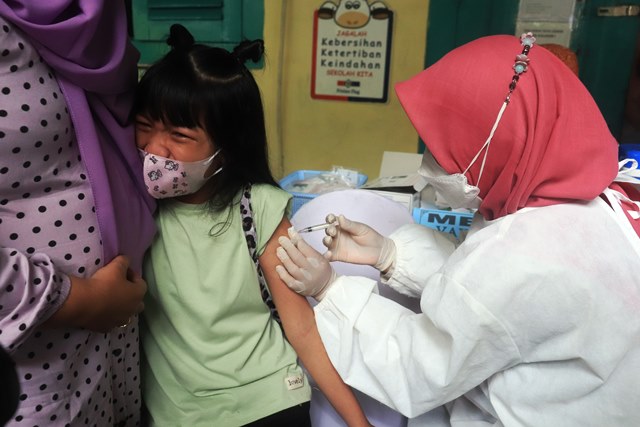 TAHAN SAKIT: Sejumlah anak anak mendapatkan suntikan vaksinasi Covid-19 di SDN Kaliasin I Surabaya. (ANDY SATRIA/RADAR SURABAYA)