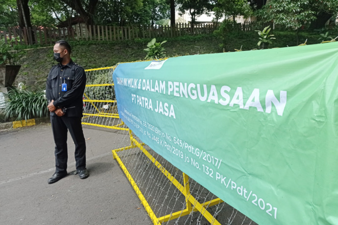 DIJAGA: Petugas keamanan berjaga di gerbang hotel Singgasana di kawasan Gunungsari, Surabaya, Selasa (18/1). (SURYANTO/RADAR SURABAYA)