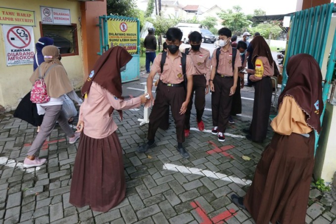 ANTUSIAS: Sejumlah siswa SMPN  34 Surabaya dicek suhu tubuhnya sebelum mengikuti pembelajaran tatap muka (PTM), Kamis (6/1). (SURYANTO/RADAR SURABAYA)