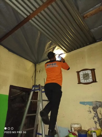 DITANGGUNG: Petugas BPBD Surabaya memperbaiki rumah yang rusak di kawasan Wiyung. (HUMAS BPBD SURABAYA)