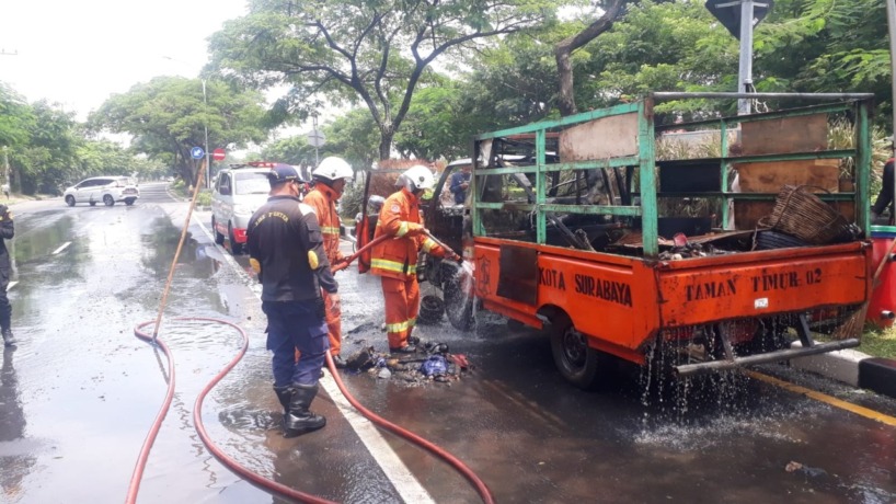 Petugas melakukan pembasahan mobil pikap DLH Surabaya di kawasan MERR Surabaya. (IST)