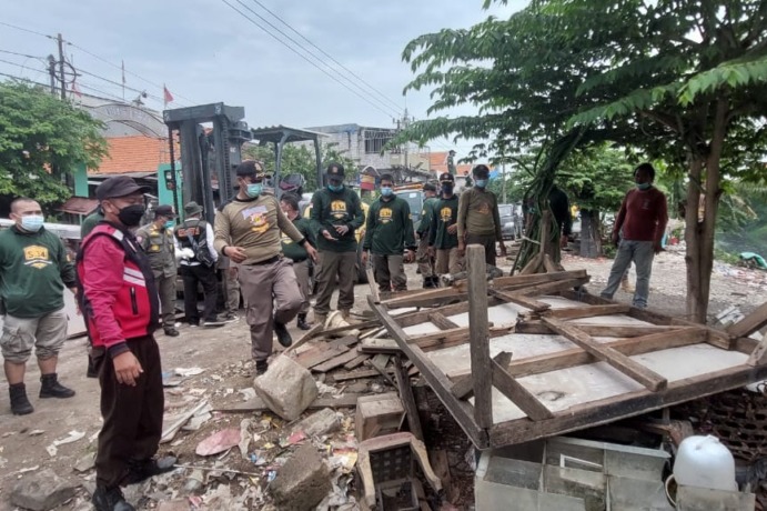 Petugas membongkar bangunan liar di bantaran Kali Tebu, Kenjeran, Surabaya. (RAHMAT SUDRAJAT/RADAR SURABAYA)