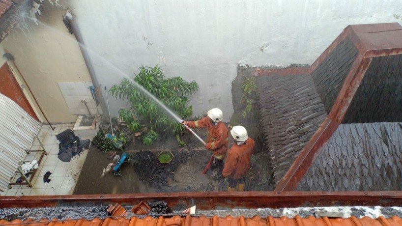 SIGAP: Petugas damkar berusaha menjinakkan api yang membakar rumah di Ngagel Jaya Tengah, Surabaya. (IST)