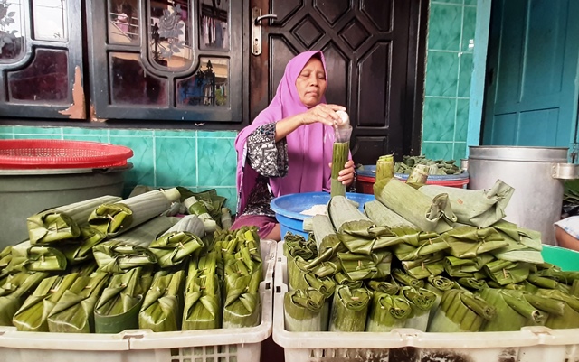 TELATEN: Salah satu pembuat lontong, Sutri, 63, sedang memasukkan beras ke dalam daun pisang, Kamis (10/3). (MAHRUS/RADAR SURABAYA)