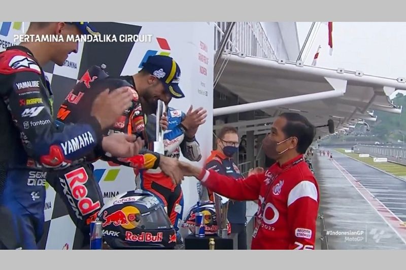 Presiden Joko Widodo (kanan) menyalami pebalap tim Red Bull KTM asal Portugal Miguel Oliveira seusai menyerahkan trofi juara seri kedua MotoGP 2022 Grand Prix Indonesia di Sirkuit Pertamina Mandalika, Lombok Tengah, Nusa Tenggara Barat, Minggu (20/3/2022)