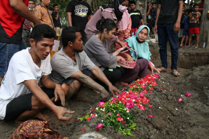 KHUSYUK BERDOA: Keluarga korban berdoa dan menabur bunga di atas makam salah seorang korban kecelakaan bus wisata. (IST)