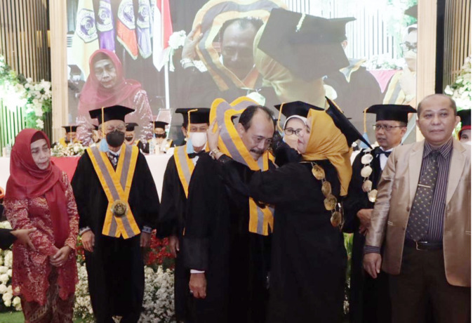 SIMBOLIS: Rektor Siti Marwiyah menyematkan samir guru besar kepada Prof Slamet Riyadi disaksikan istri dan jajaran guru besar Unitomo. (ISTIMEWA)
