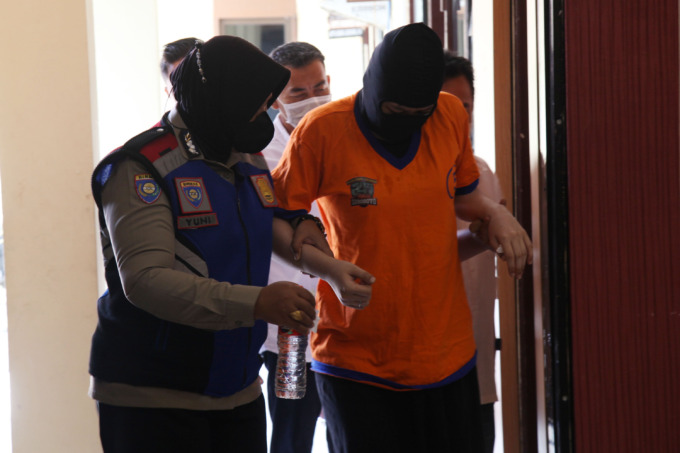 GELAP MATA: Petugas menggiring tersangka pembuang bayi yang berhasil diamankan di Mapolsek Wonocolo, Surabaya, Jumat (10/6).  (SURYANTO/RADAR SURABAYA)