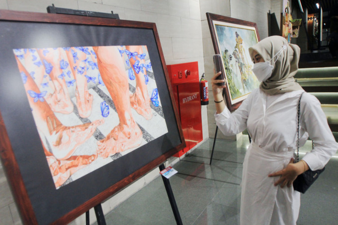 MEDIA CAT AIR: Pengunjung mengamati karya-karya lukis cat air karya seniman dari Komunitas Lukis Cat Air Indonesia yang dipamerkan di Basemen Alun-Alun Surabaya, Jumat (8/7). (ANDY SATRIA/RADAR SURABAYA)