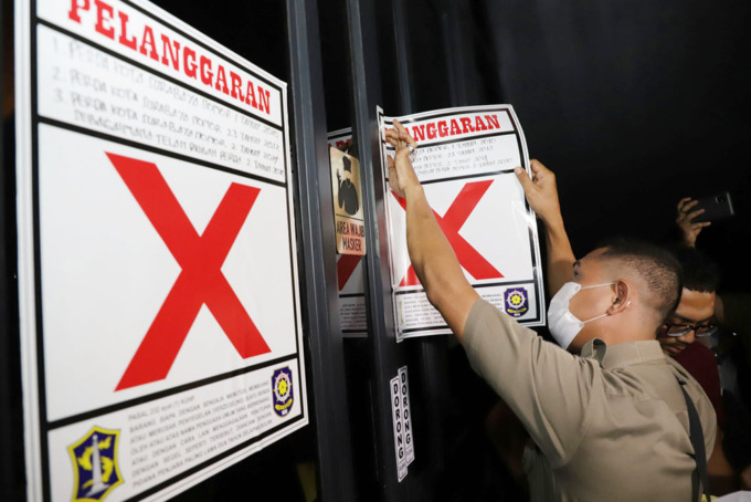 Petugas Satpol PP Kota Surabaya memasang segel pada pintu masuk Holywing di kawasan Jalan Basuki Rahmat, Surabaya. (SURYANTORADAR SURABAYA)