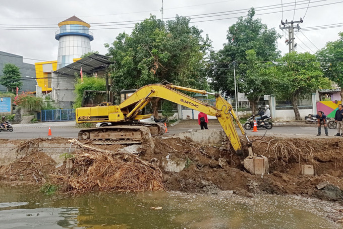 BARU MULAI MINGGU: Dengan menggunakan alat berat pekerja menyelesaikan pengerjaan proyek plengsengan sungai di Jalan Arif Rahman Hakim, Surabaya, Minggu (14/8). (SURYANTO/RADAR SURABAYA)