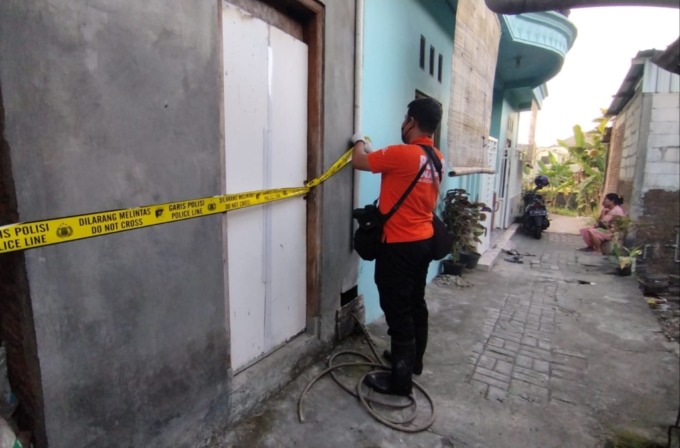 TERLARANG: Petugas memasang police line di rumah jagal anjing di Jalan Pesapen IV, Sumur Welut, Lakarsantri, Surabaya. (MAHRUS/RADAR SURABAYA)