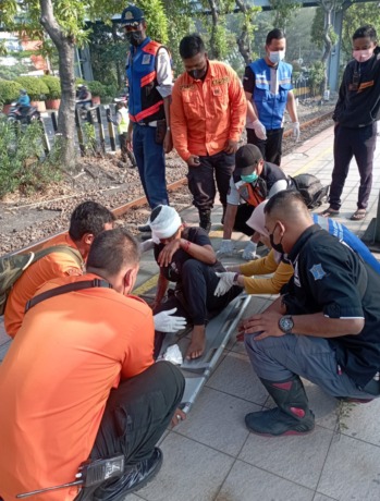 LUKA-LUKA: Petugas memberikan penanganan awal kepada Mariyatul Kiptiyah yang terserempet kereta api di Jalan Ahmad Yani, Surabaya, Selasa (6/9). (IST)
