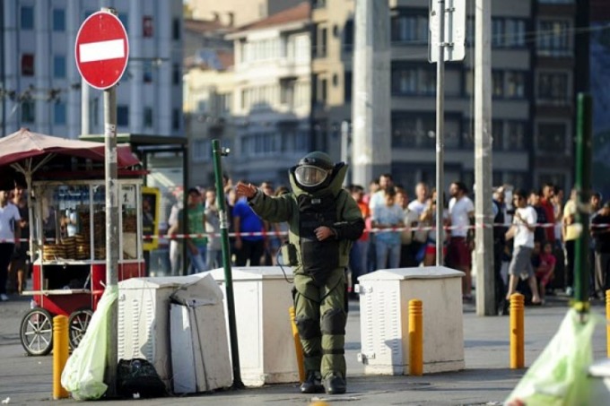 Petugas penjinak bom memperingatkan warga untuk menjauh saat ia mulai memeriksa paket mencurigakan di Lapangan Taksim di pusat kota Istanbul, Turki, Minggu (26/7). Polisi Turki meledakkan paket mencurigakan yang ditemukan di Lapangan Taksim, di pintu masu